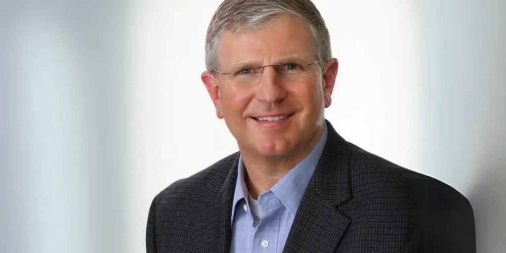 A man with grey hair and glasses wearing a suit.
