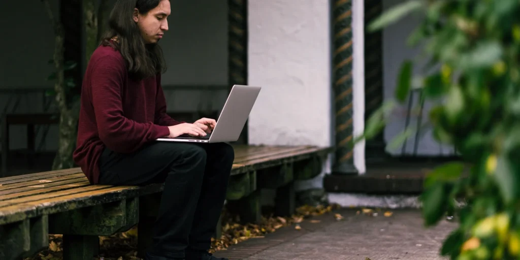 A person sitting on a bench with a laptop