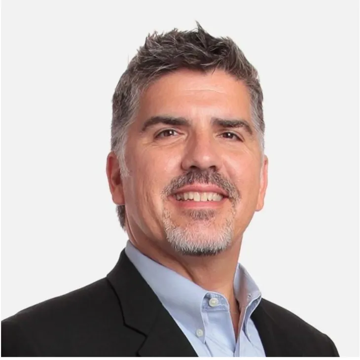 A man with grey hair and a blue shirt.