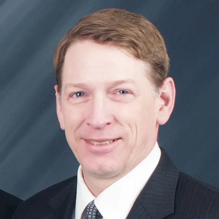 A man in suit and tie smiling for the camera.