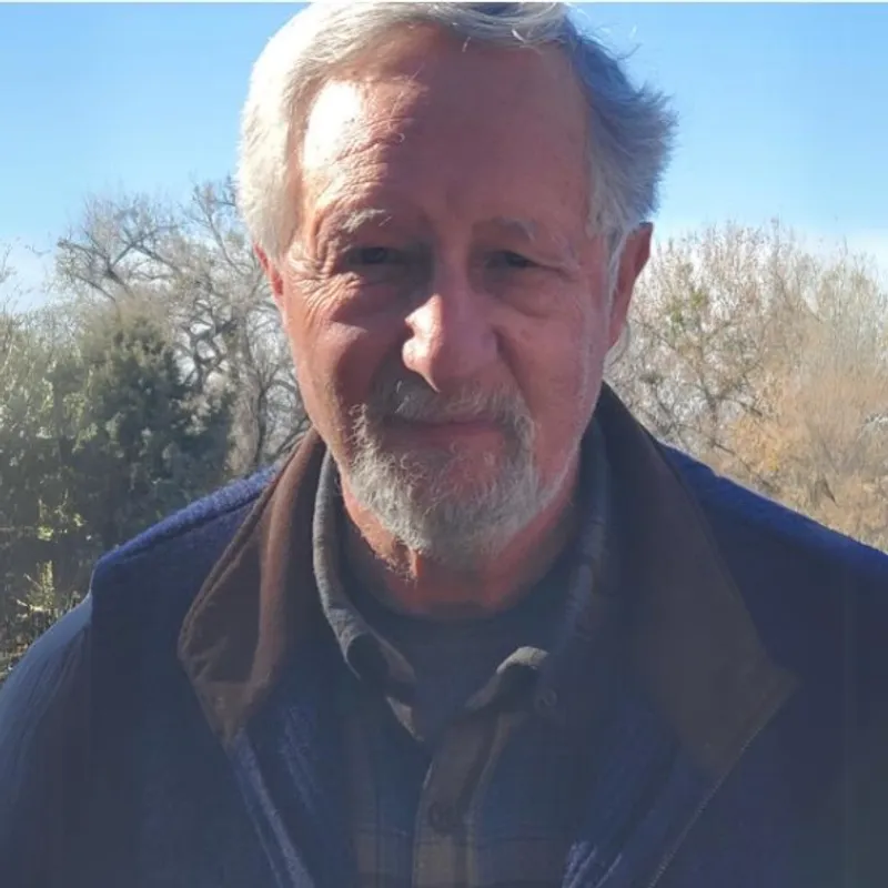 A man with grey hair and beard wearing a jacket.