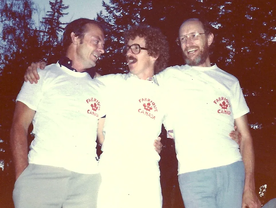 Three men standing next to each other in white shirts.